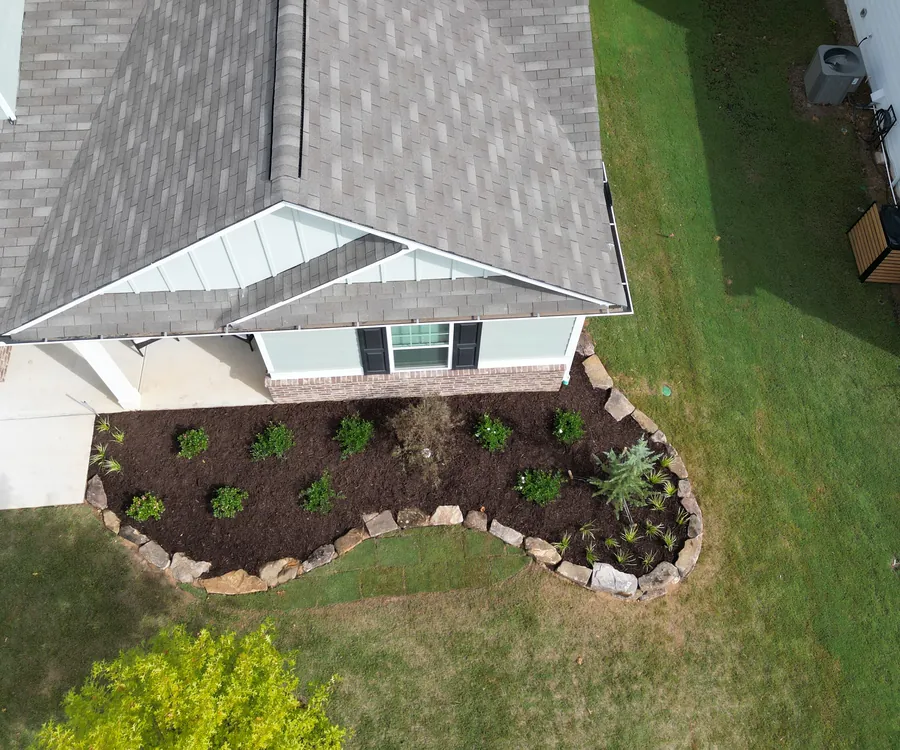 Aerial view of a curved, stone-edged planting bed with fresh plantings and lawn at an Acworth, Georgia home