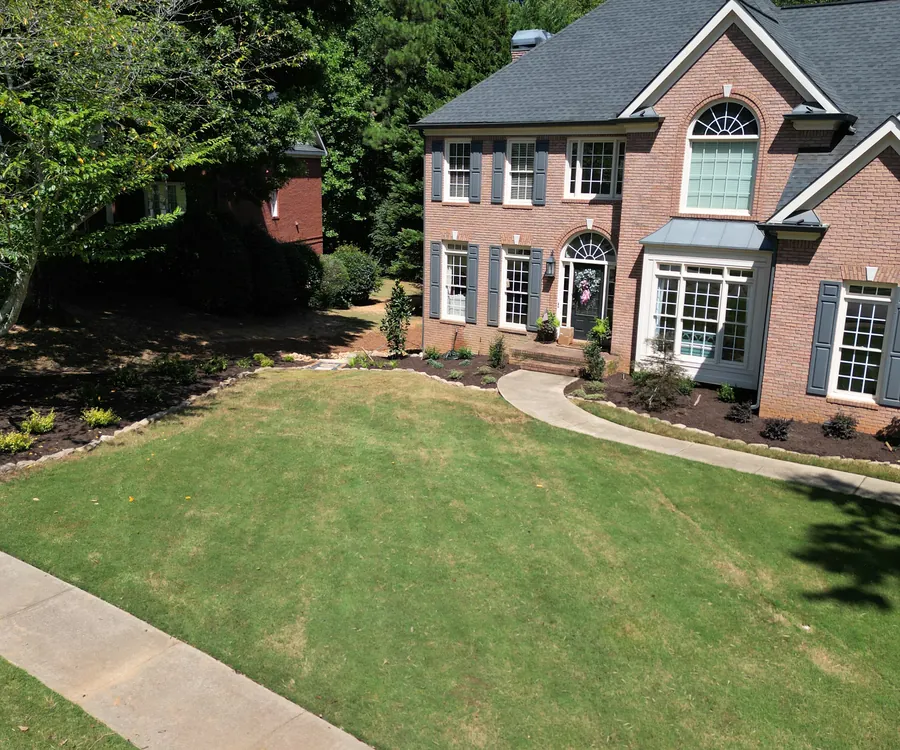 Brick home with a fresh-cut lawn and tidy foundation landscaping by KalKare in Acworth, Georgia