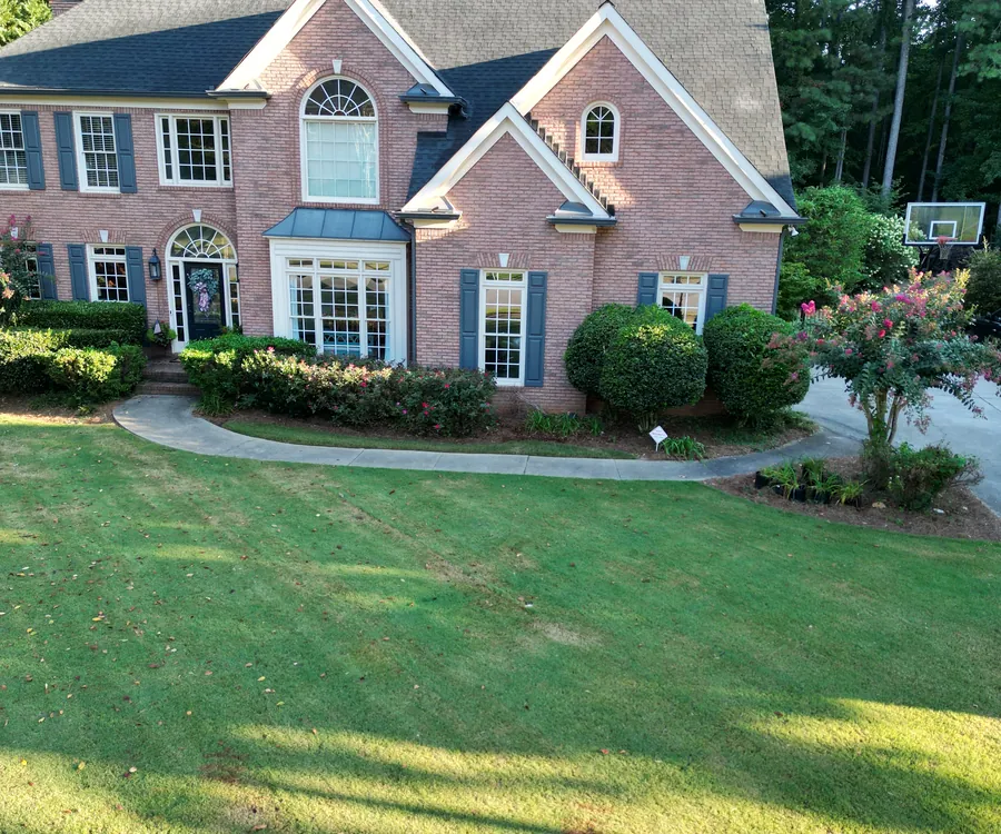 Brick two-story home with a manicured front lawn and shaped shrubs, landscaped by KalKare in Acworth, Georgia