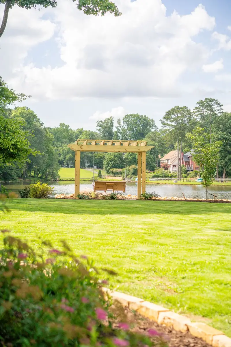 Cedar pergola centered on a lakefront lawn.