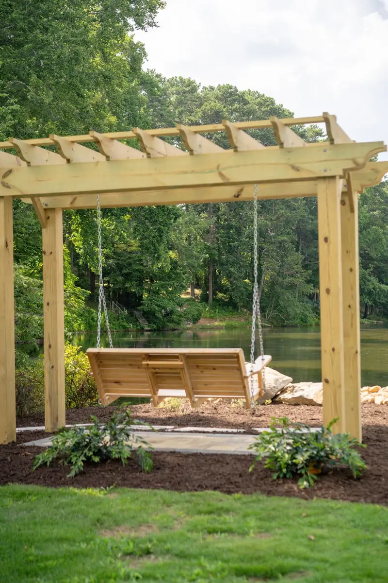 Cedar pergola with a hanging porch swing by the water.