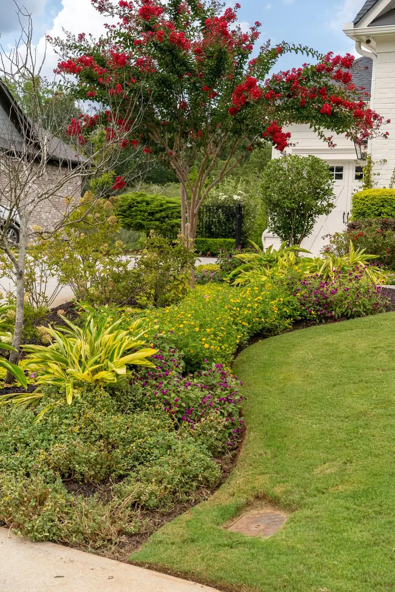 Curved flower bed sweeping around a manicured lawn.