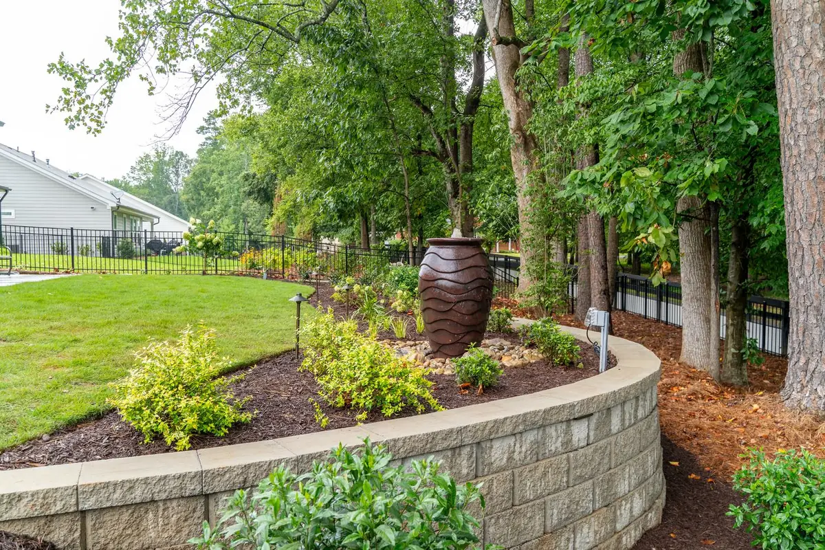 Bubbling fountain urn set into a curved block retaining wall bed.