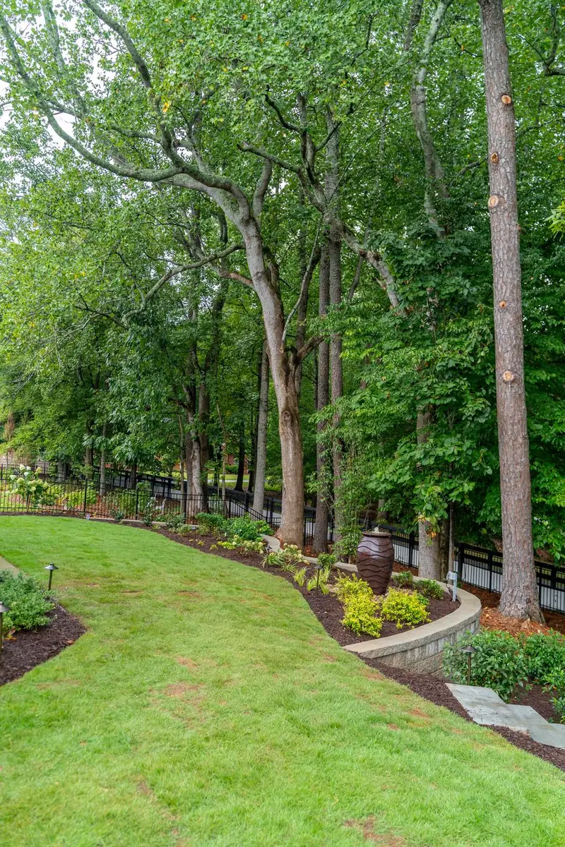 Fountain urn garden bed along a lit walkway and fence.