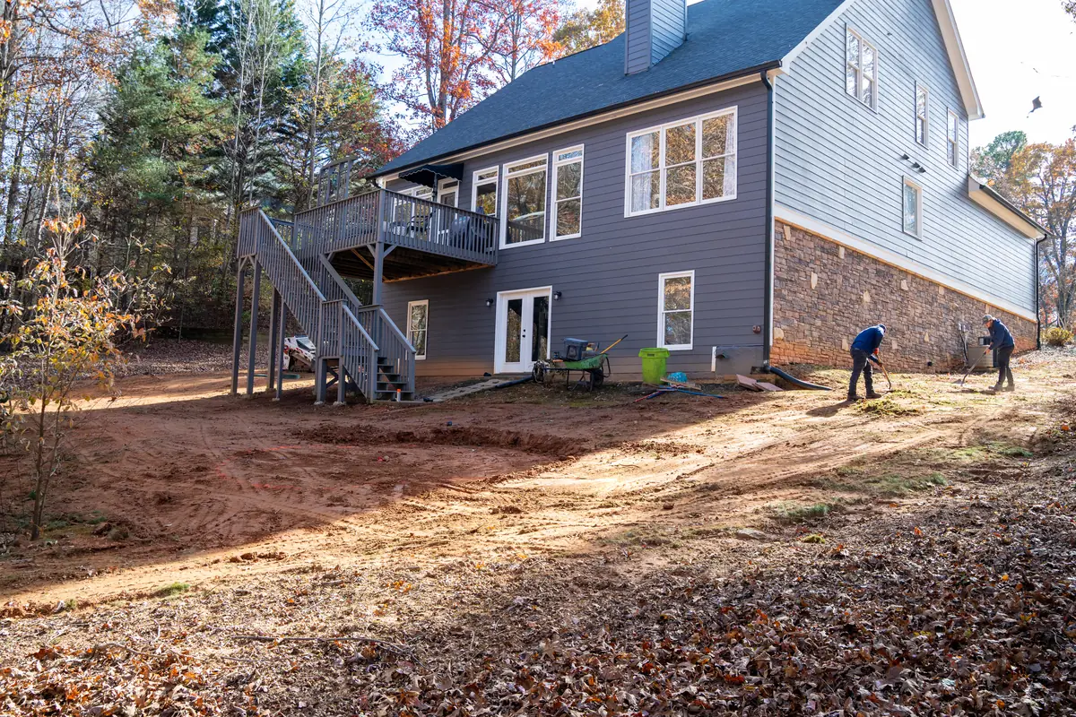 KalKare crew grading bare soil behind a home to correct slope and drainage