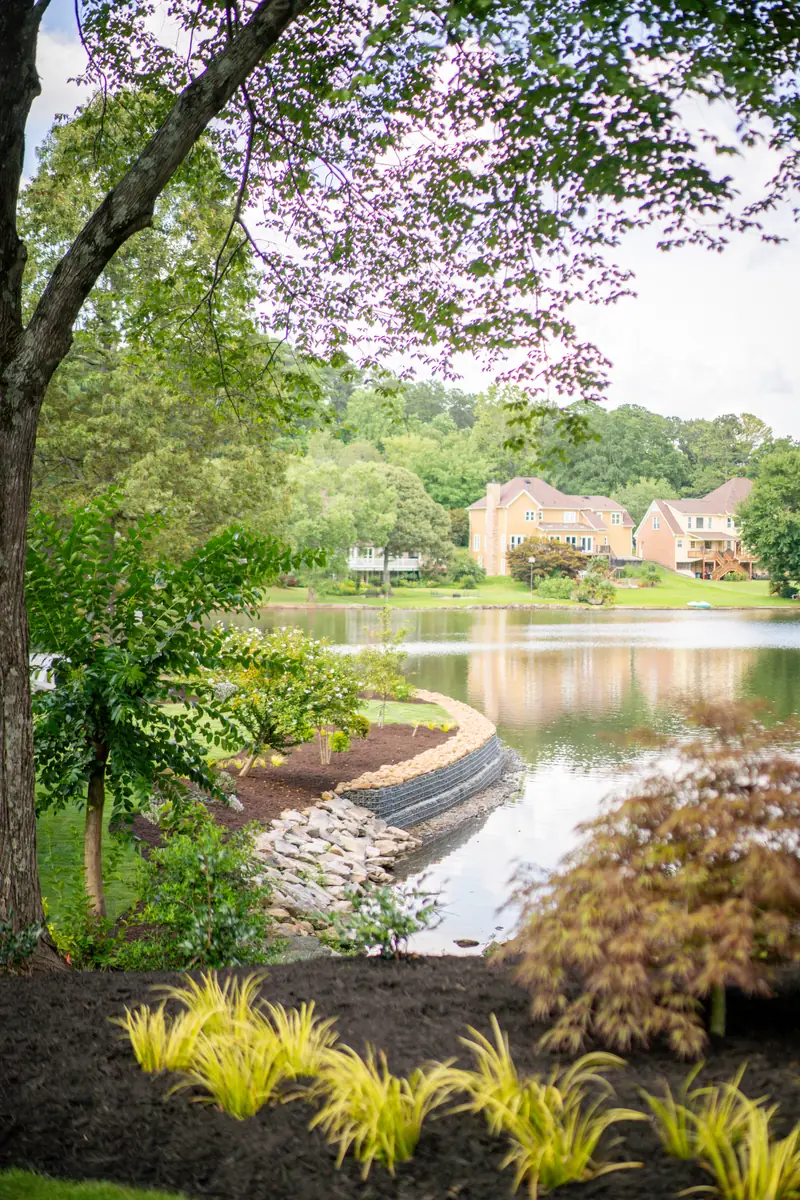 Finished, well-watered lakeside landscape with a lush lawn and established planting beds
