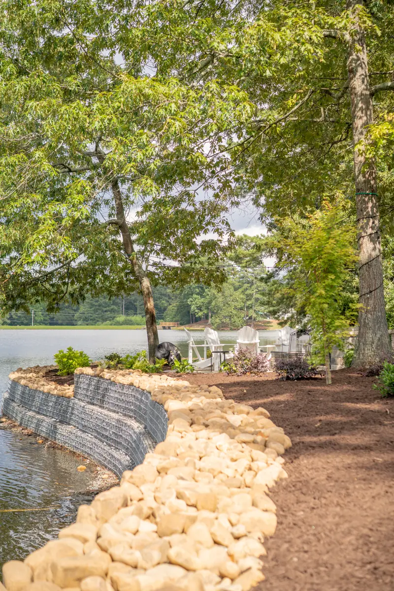 Finished shoreline with a stone retaining wall and riprap boulder edging for erosion control