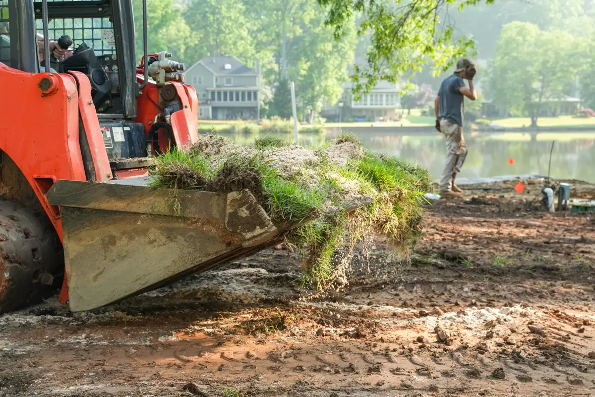 Skid steer loader moving soil during lakefront grading and excavation work