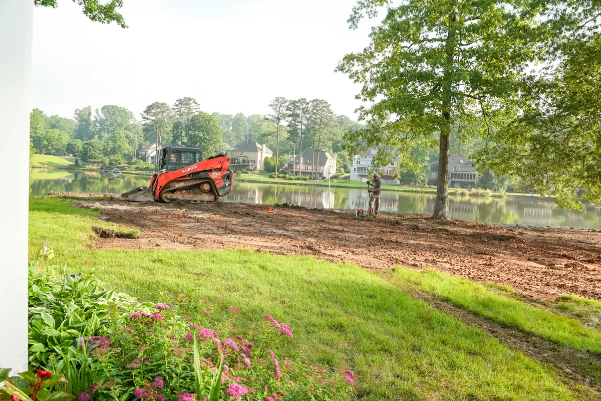 Compact track loader shaping a lakefront shoreline during earthwork