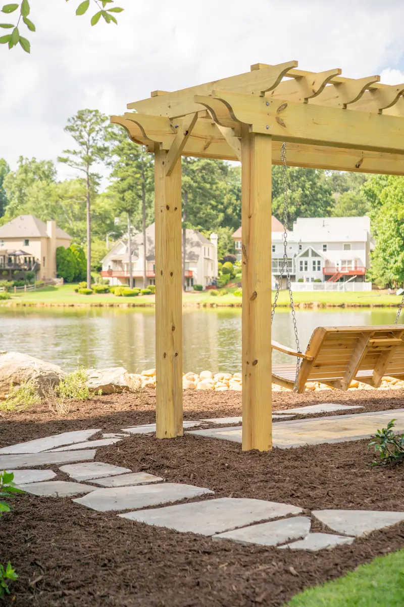 Cedar pergola with a porch swing and flagstone stepper path overlooking the lake