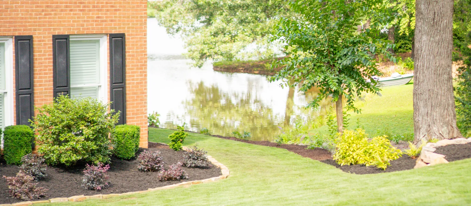 Lakeside yard with colorful foundation beds and a healthy lawn, landscaped by KalKare