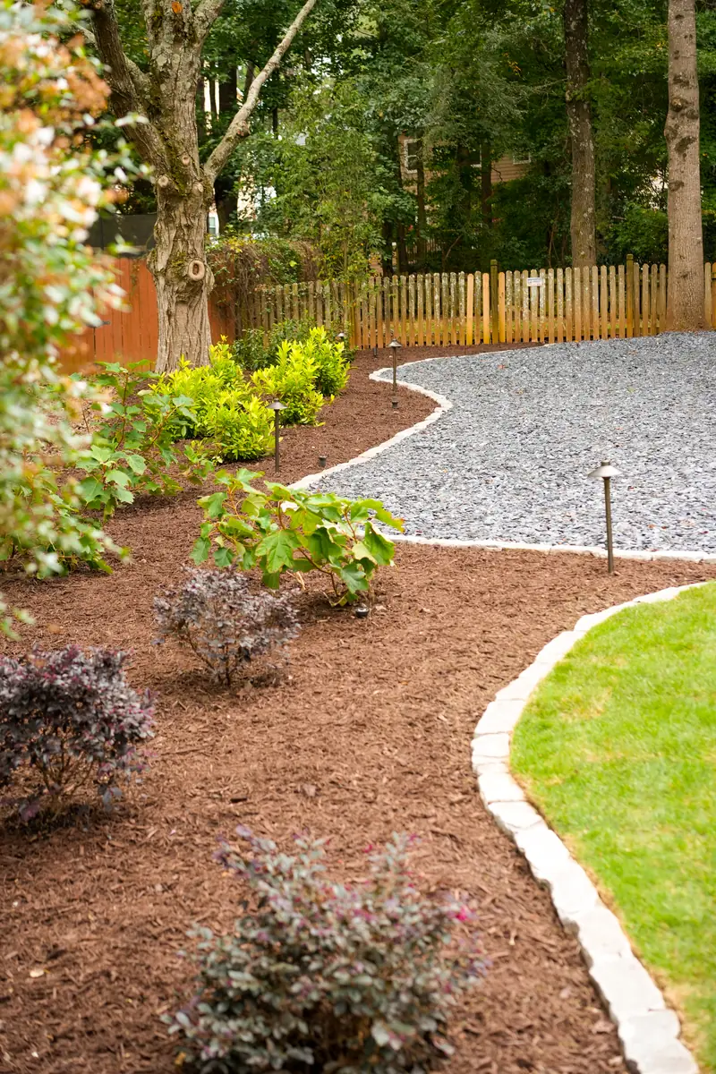 Curved gravel path edged with landscape lighting and layered planting beds