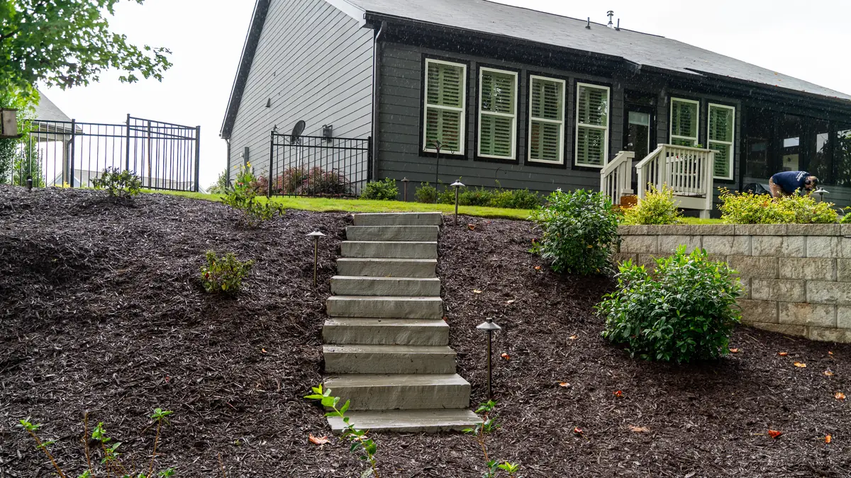 Landscape path lights lining stone steps and a mulched slope beside a home